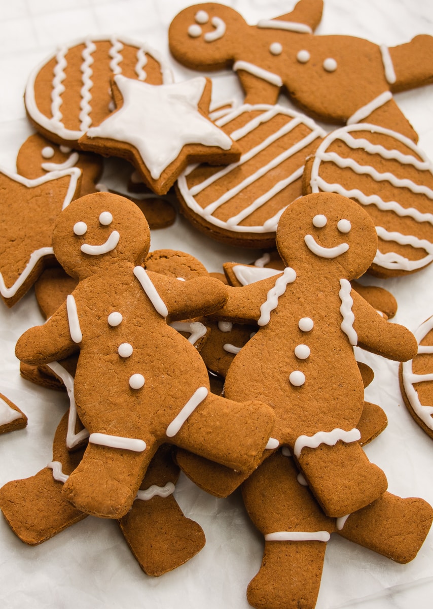 Close-up shot of 2 gingerbread people on a pile of more decorated gingerbread cookies