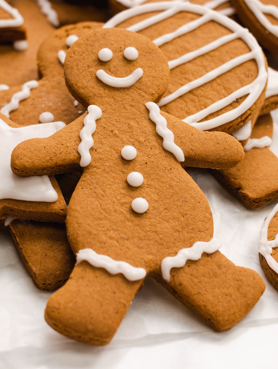 Close-up shot of a gingerbread person with icing buttons and squiggles on a pile of cookies