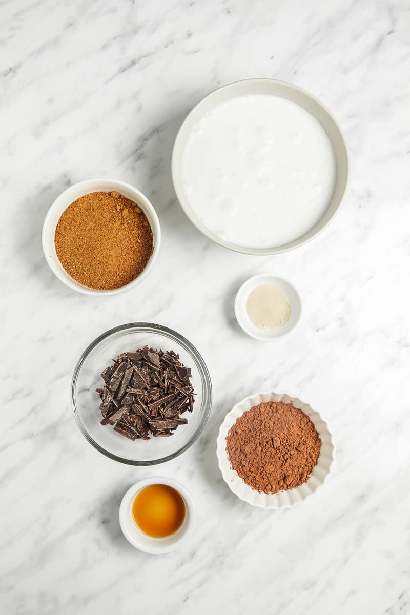 Mixing bowls of coconut cream, coconut sugar, cocoa powder, agar agar, dark chocolate, and salt