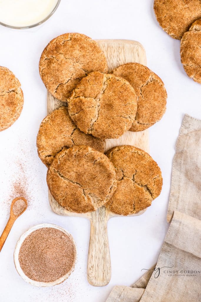 Six snickerdoodle cookies on a wooden cutting board