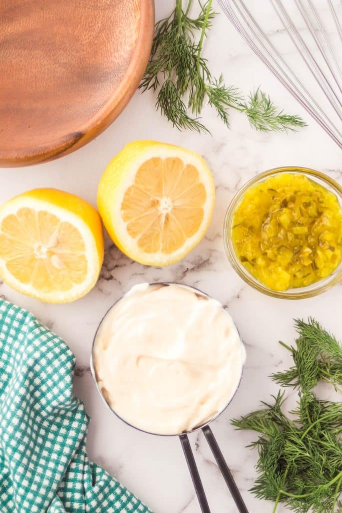 ingredients for vegan tartar sauce on a marble counter, each in separate bowls. 