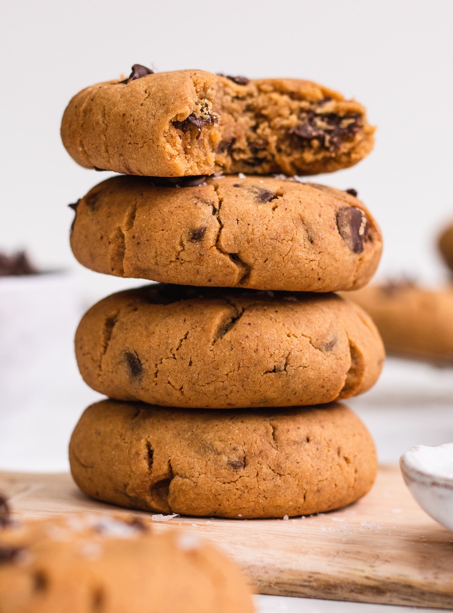 A stack of 4 vegan peanut butter cookies with a bite taken out of the top one