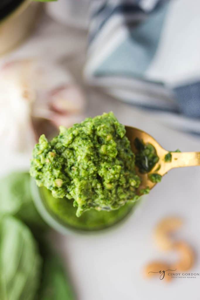 a top down view of a spoonful of pesto over a jar of pesto