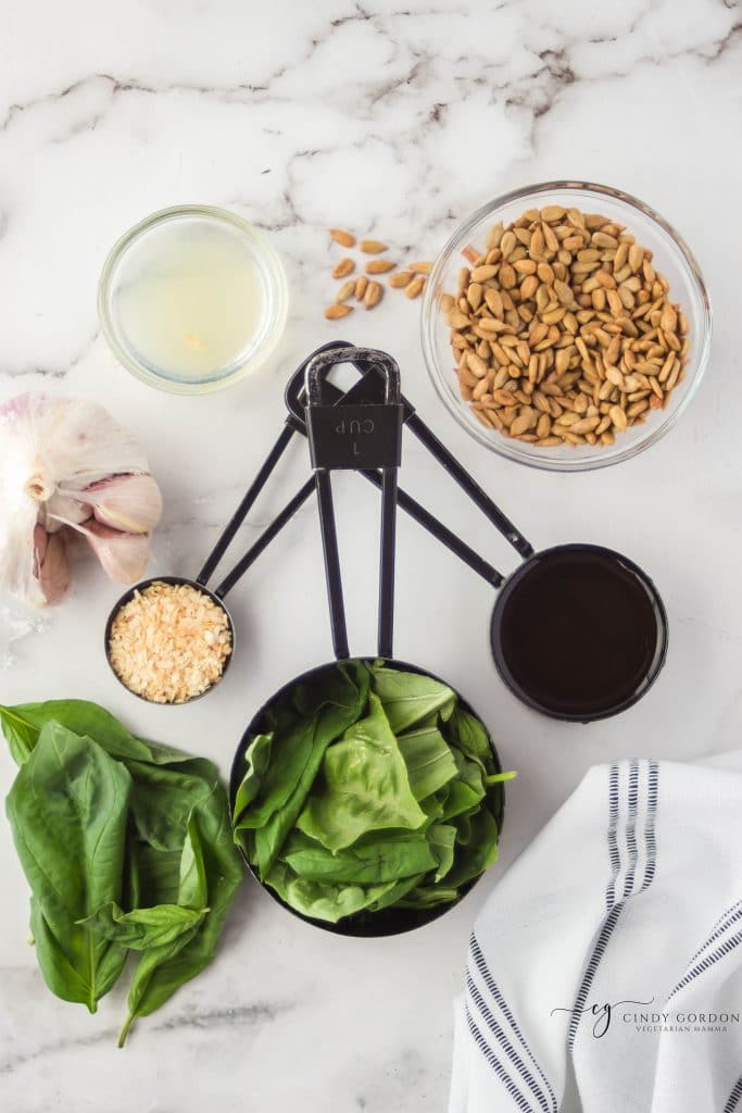 ingredients for nut free pesto arranged on a countertop in separate bowls