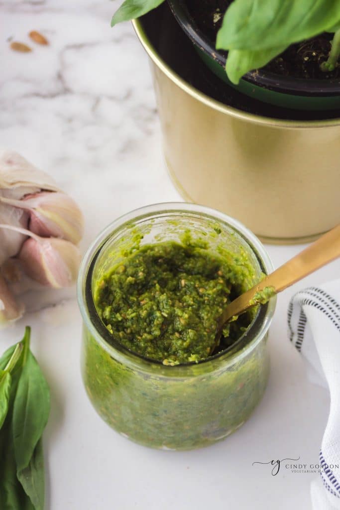 view of the inside of a small jar of nut free pesto with a gold spoon in it