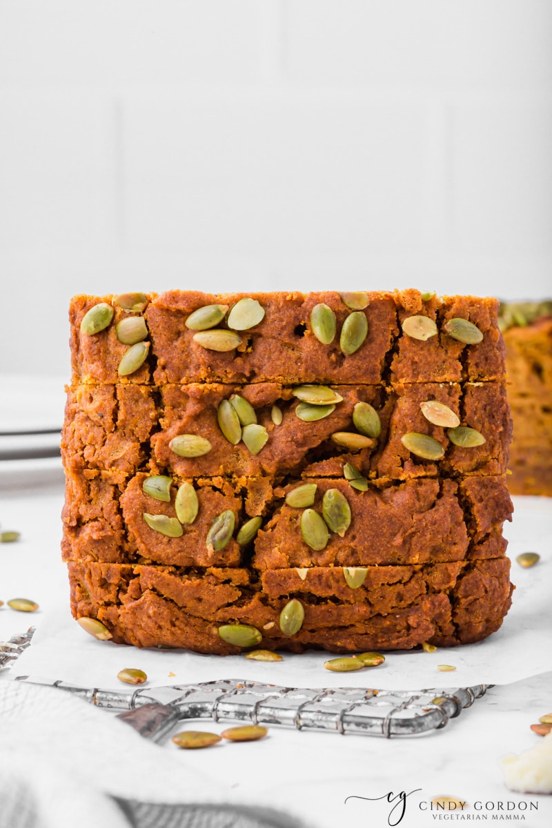 Four vertical slices of vegan pumpkin bread on a sheet of parchment paper