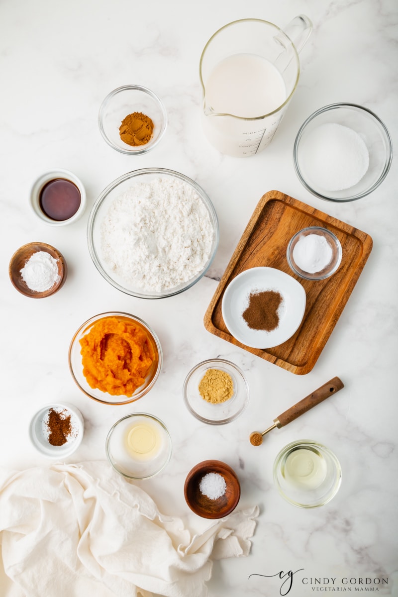 Bowls of flour, milk, sugar, salt, cinnamon, pumpkin puree, cinnamon, nutmeg, ginger, and cloves