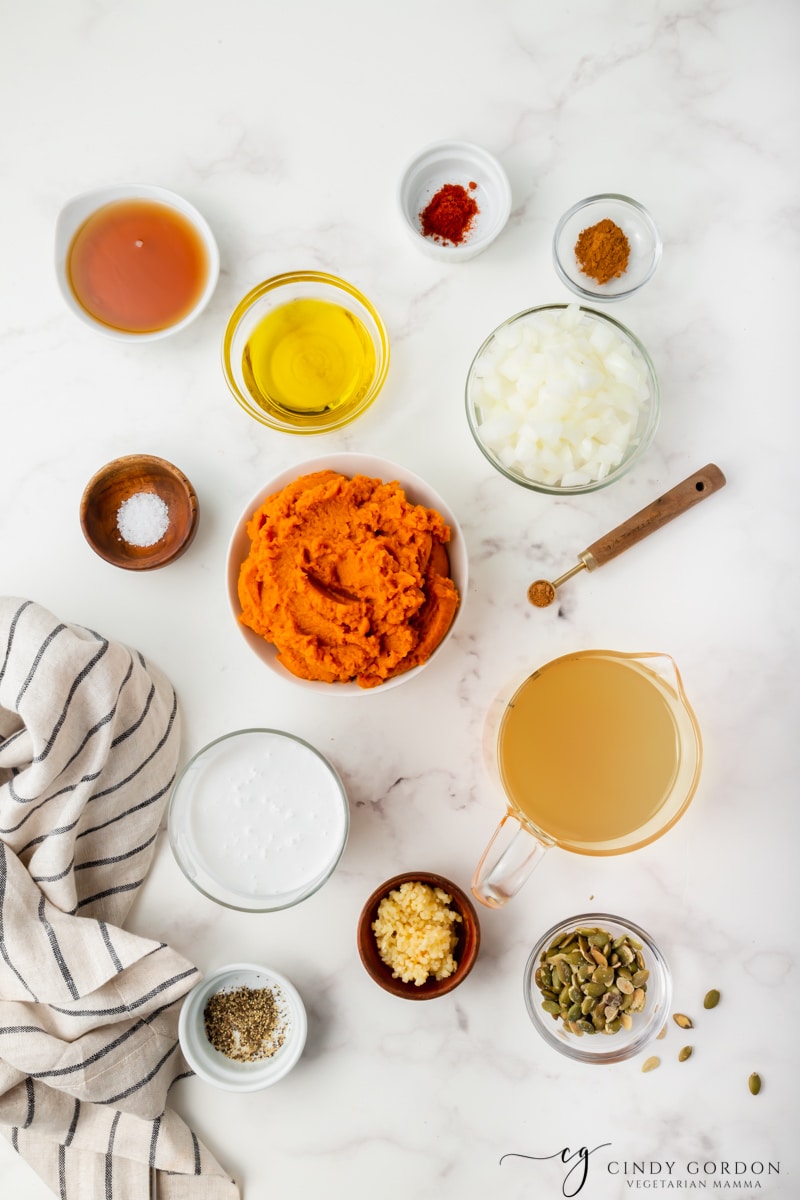 Bowls of pumpkin puree, onion, oil, paprika, nutmeg, salt, cinnamon, and vegetable broth