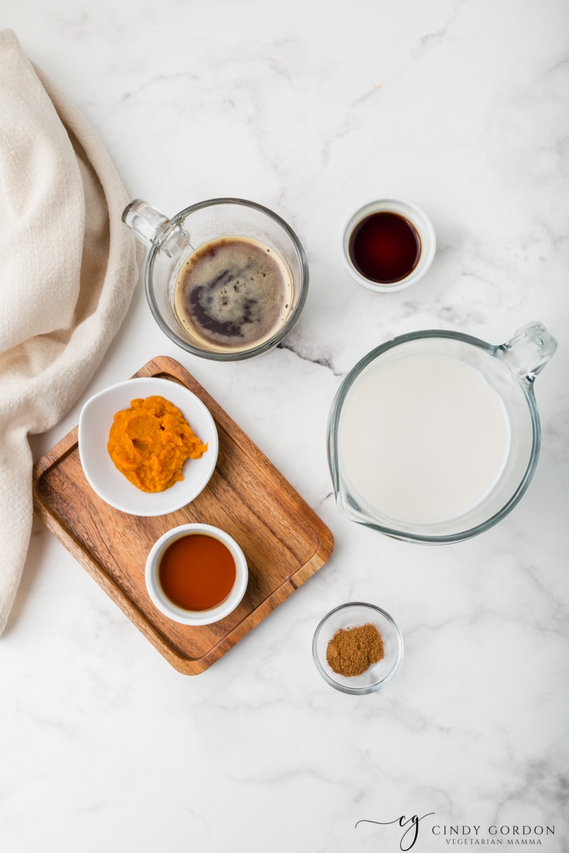 Bowls of non-dairy milk, pumpkin puree, maple syrup, vanilla extract, espresso, and pumpkin pie spice