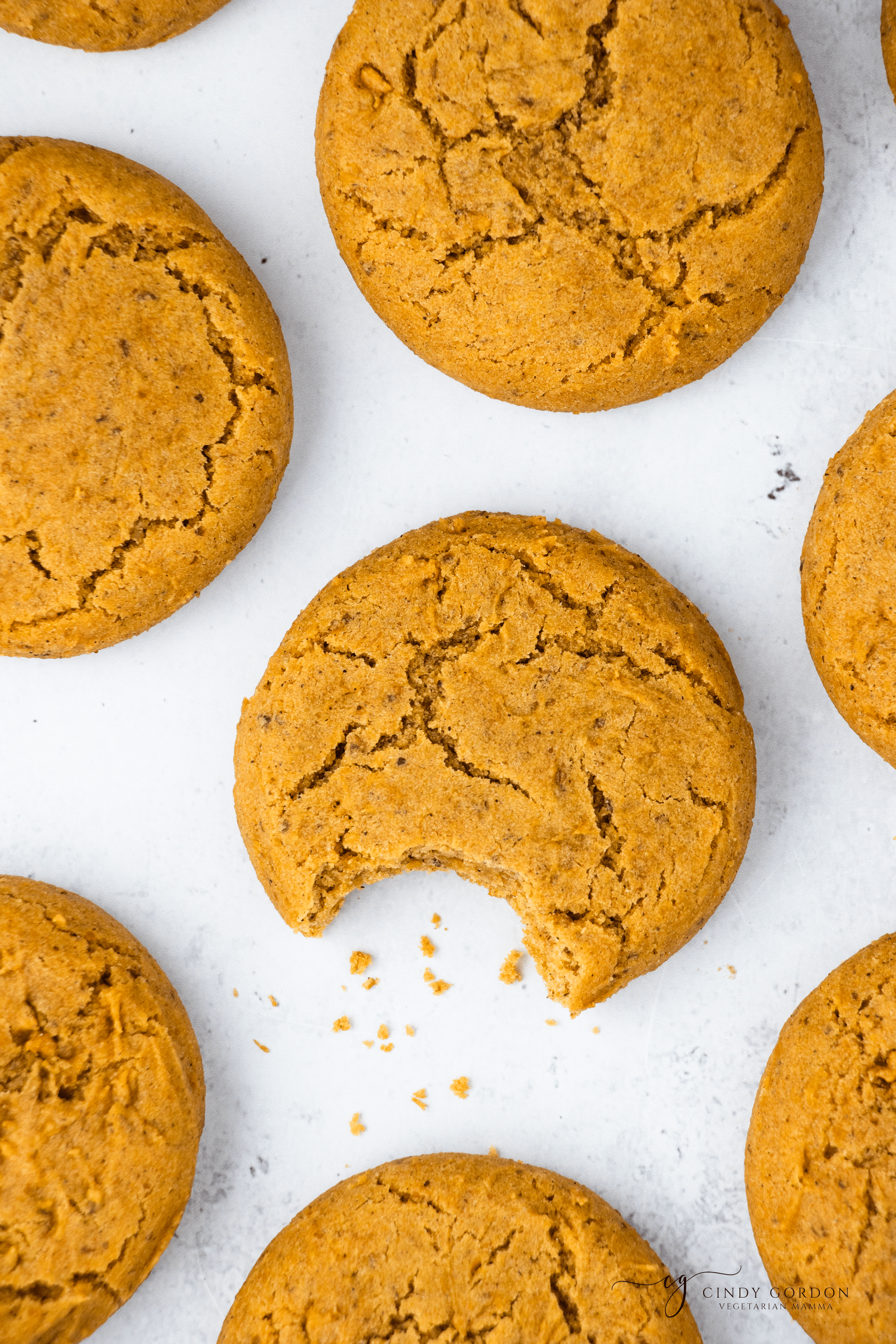 Vegan pumpkin cookies on a countertop with a bite taken from one
