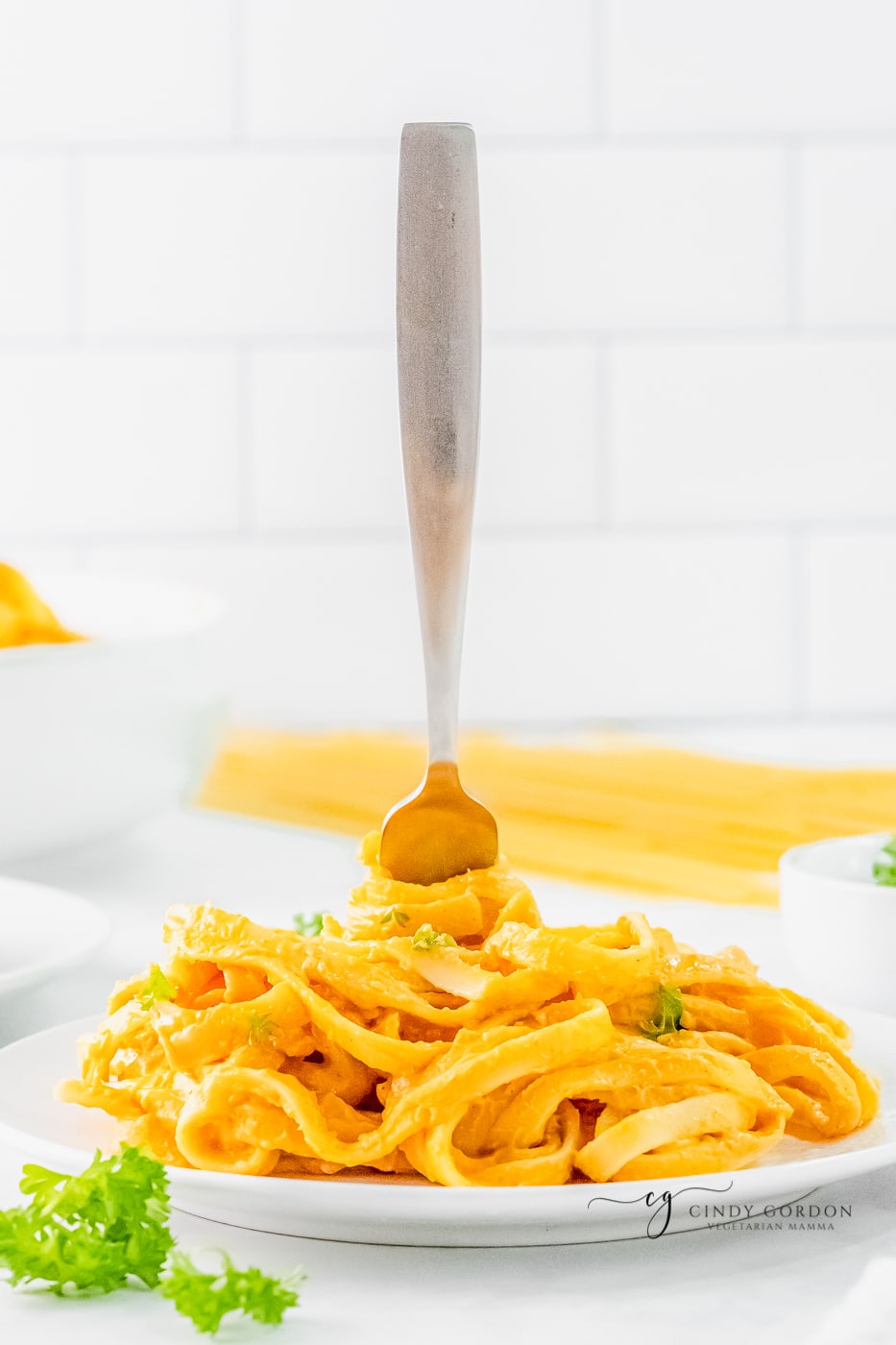 a plate of pumpkin pasta with a fork sticking up in the middle. 