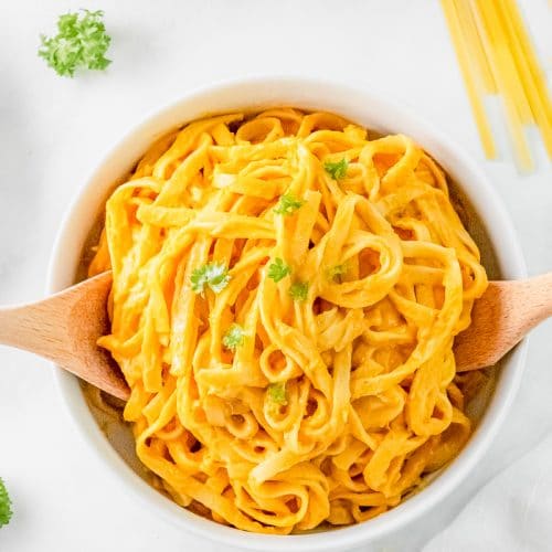 a serving bowl filled with fettucini with pumpkin alfredo sauce.