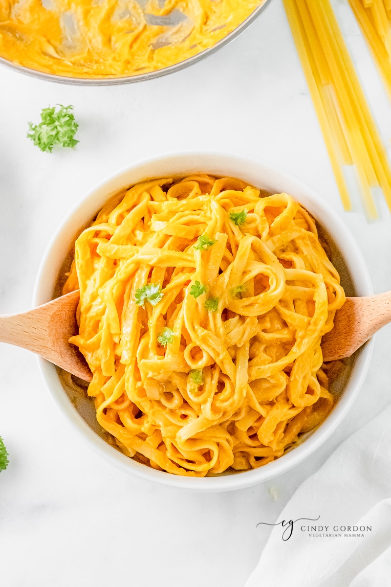 a serving bowl filled with fettucini with pumpkin alfredo sauce.