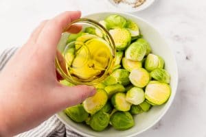 halved green brussel sprouts with oil being poured over it