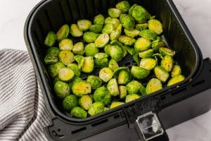 uncooked halved brussel sprouts in black air fryer basket