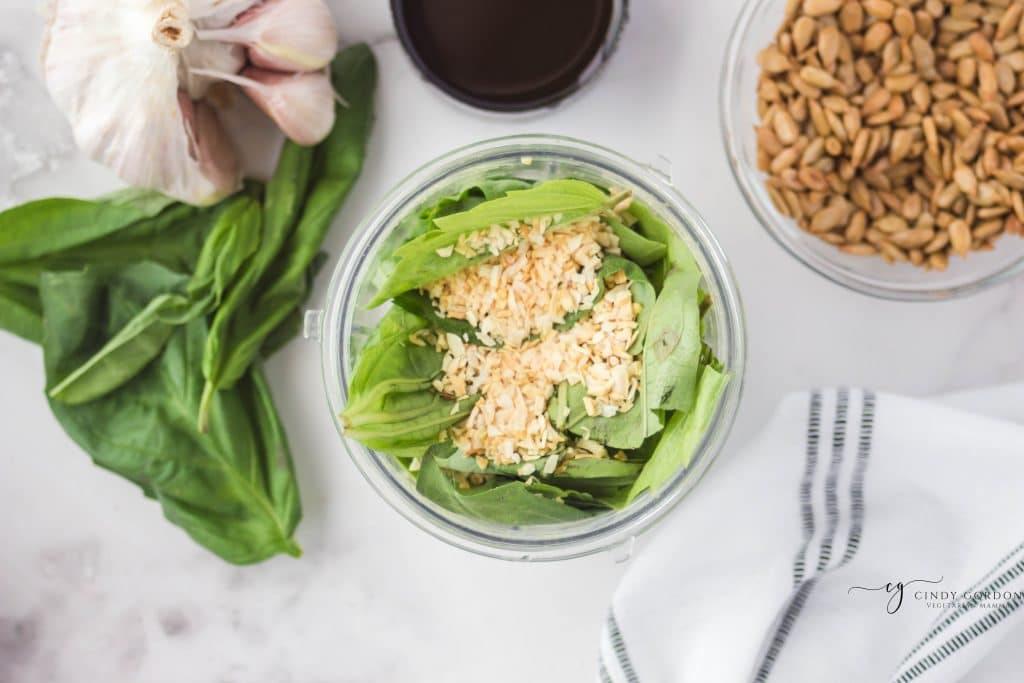 overhead shot of brown crumbles on top of basil in a clear cup