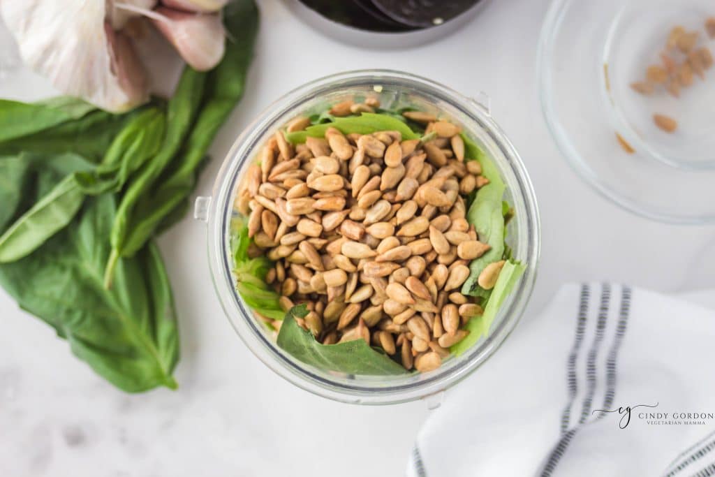 overhead shot of brown seeds on top of basil in a clear cup