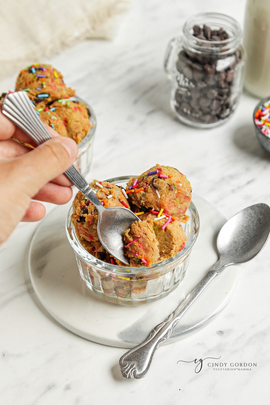 A hand taking a bite of chickpea cookie dough with a small spoon