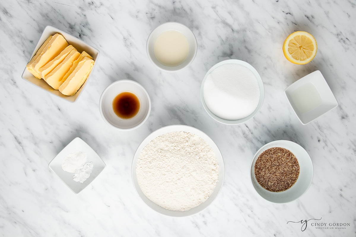 White bowls of flour, sugar, vanilla, flax egg, butter, almond milk, and xanthan gum