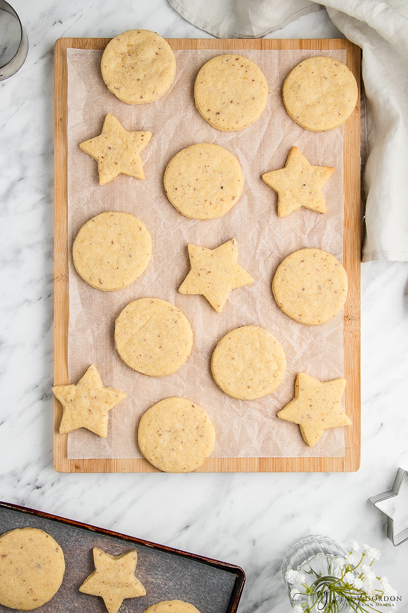 14 vegan sugar cookies on parchment paper on a wooden cutting board