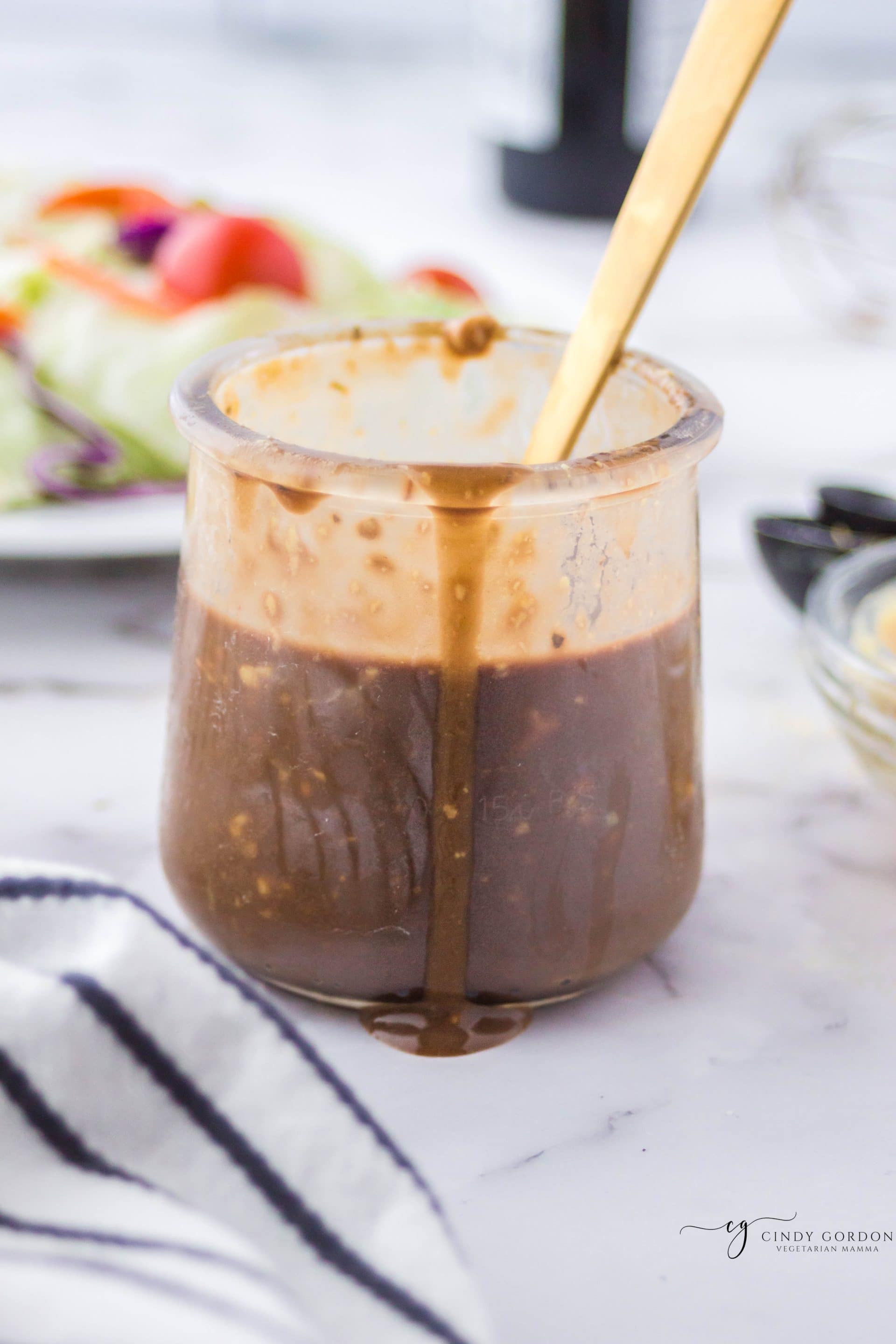 A clear jar full of balsamic vinaigrette dressing with some dripping down the side