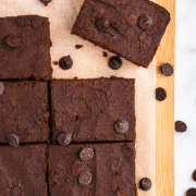 8 brownies on a cutting board with parchment paper surrounded by chocolate chips