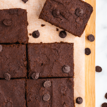 8 brownies on a cutting board with parchment paper surrounded by chocolate chips