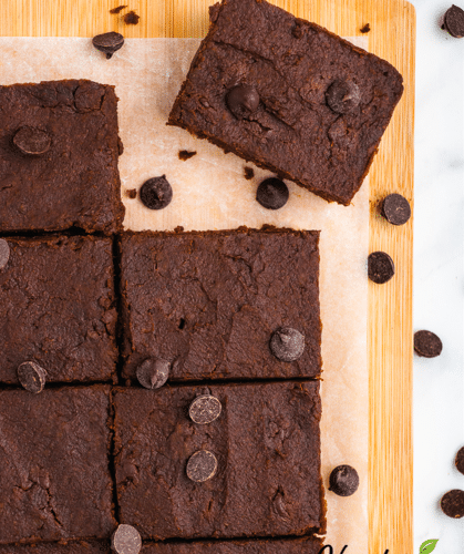 8 brownies on a cutting board with parchment paper surrounded by chocolate chips