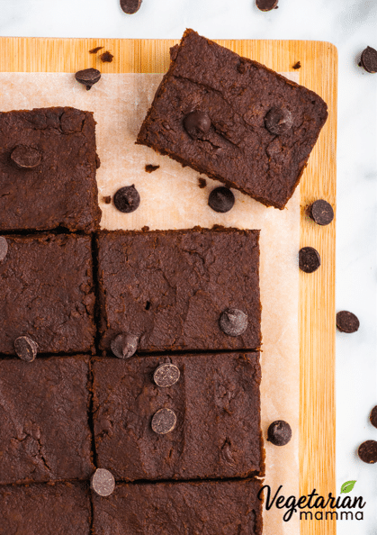 8 brownies on a cutting board with parchment paper surrounded by chocolate chips