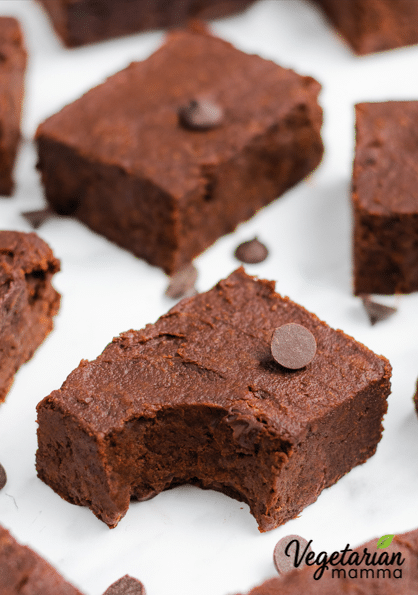 A sweet potato brownie with a bite missing surrounded by more brownies and chocolate chips