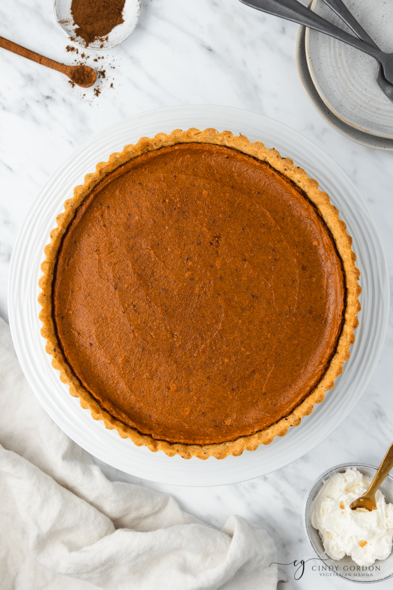 Whole vegan sweet potato pie with gluten-free crust on a marble countertop