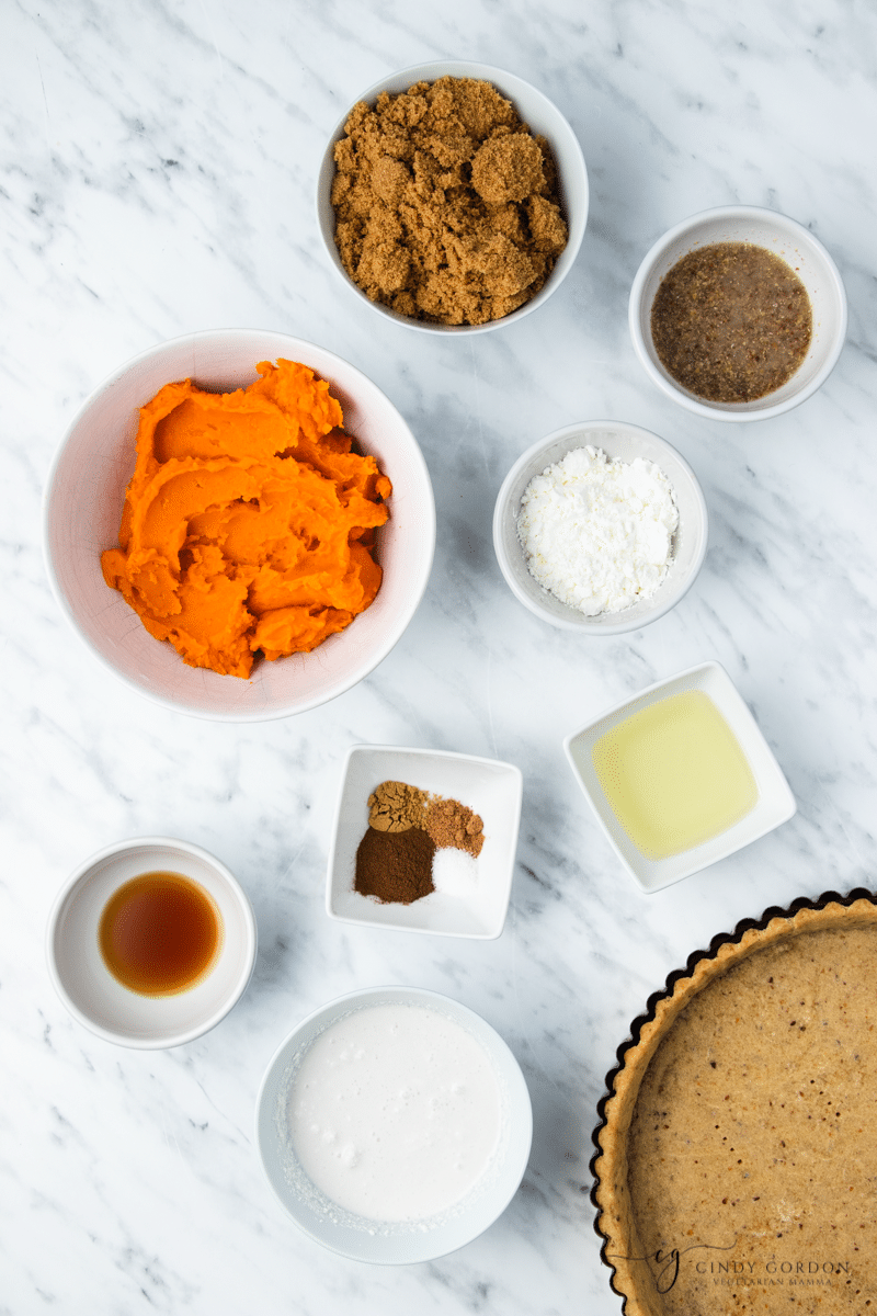 White bowls of sweet potato puree, brown sugar, flax egg, oil, spices, and a pie crust