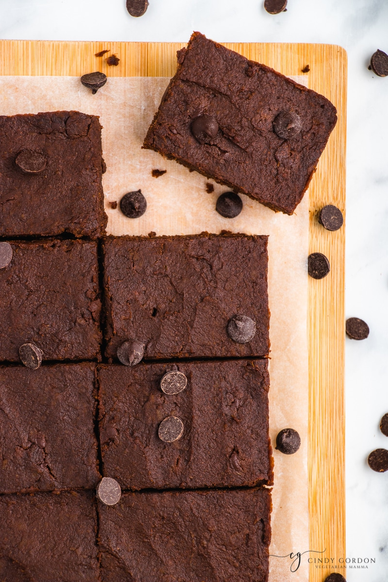 8 brownies on a cutting board with parchment paper surrounded by chocolate chips