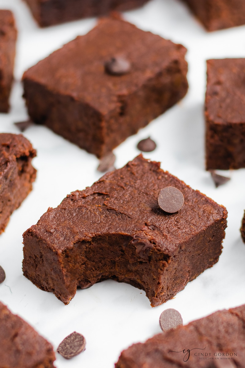 A sweet potato brownie with a bite missing surrounded by more brownies and chocolate chips