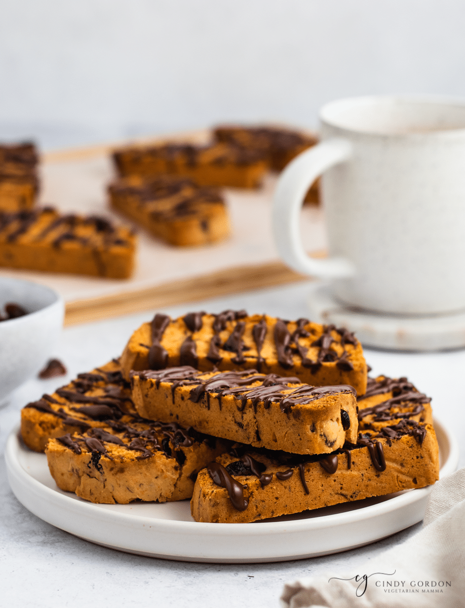 A plate of biscotti covered in chocolate next to a cup of coffee