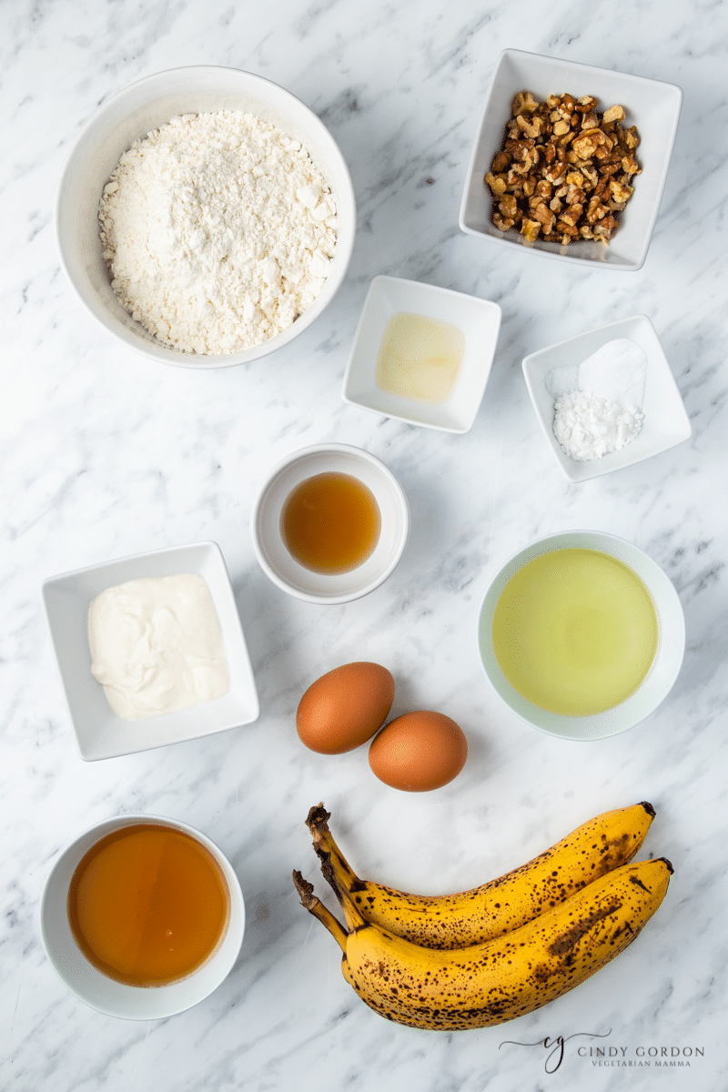 Bowls of flour, walnuts, eggs, oil, vanilla extract, and yogurt