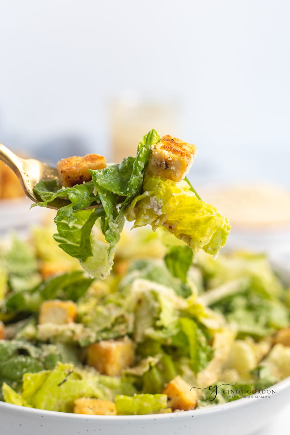 Close-up shot of a bite of Caesar salad with dressing, Parmesan cheese, and croutons