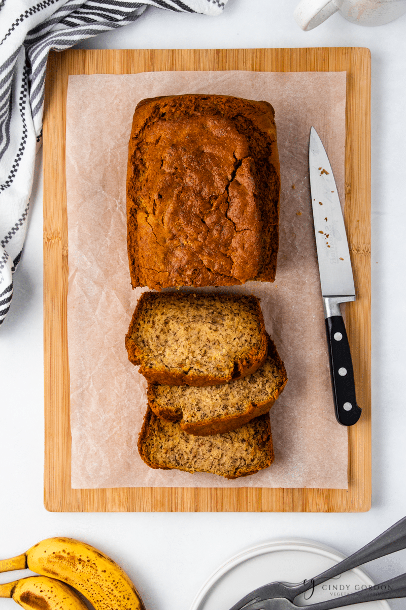 Overhead shot of a loaf of bread with 3 slices cut next to a knife