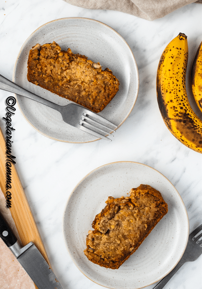 Two white plates with a slice of banana bread on each.