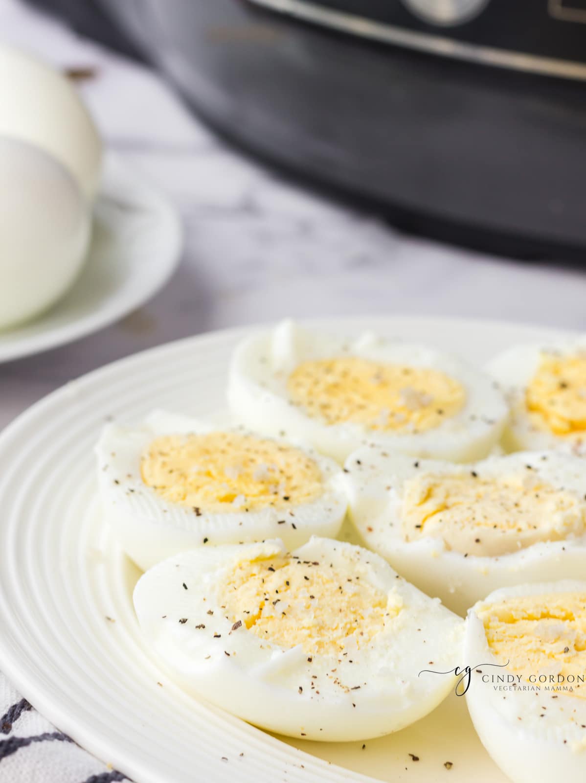 a white plate full of hard boiled egg halves topped with salt and pepper
