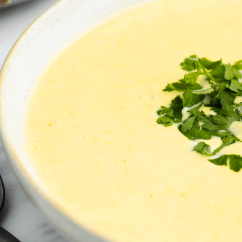 a closeup of the left half of a bowl of creamy corn potage soup.
