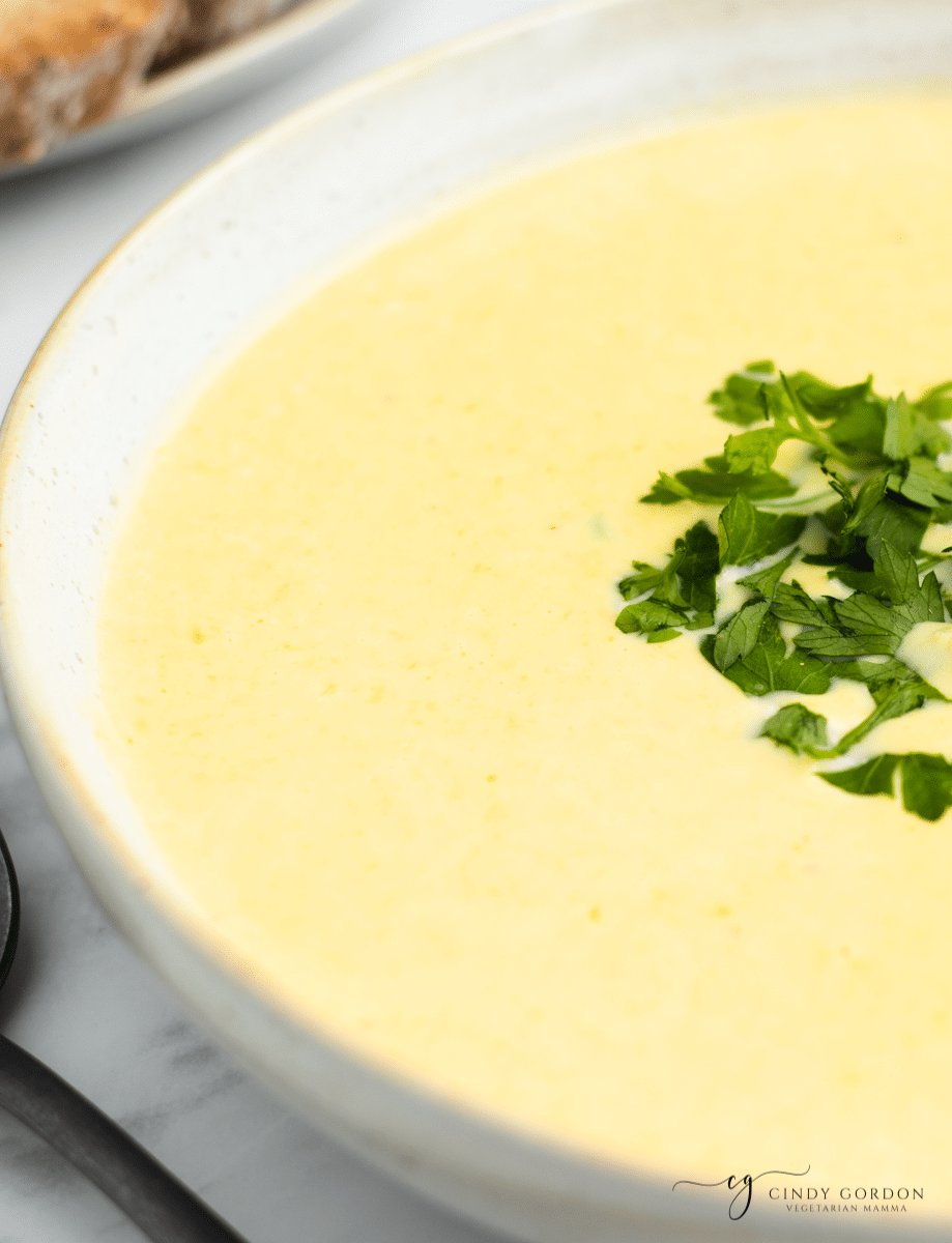 a closeup of the left half of a bowl of creamy corn potage soup. 