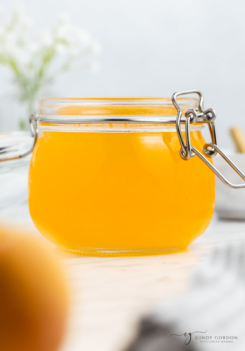 a rounded glass jar with bail top billed with peach simple syrup