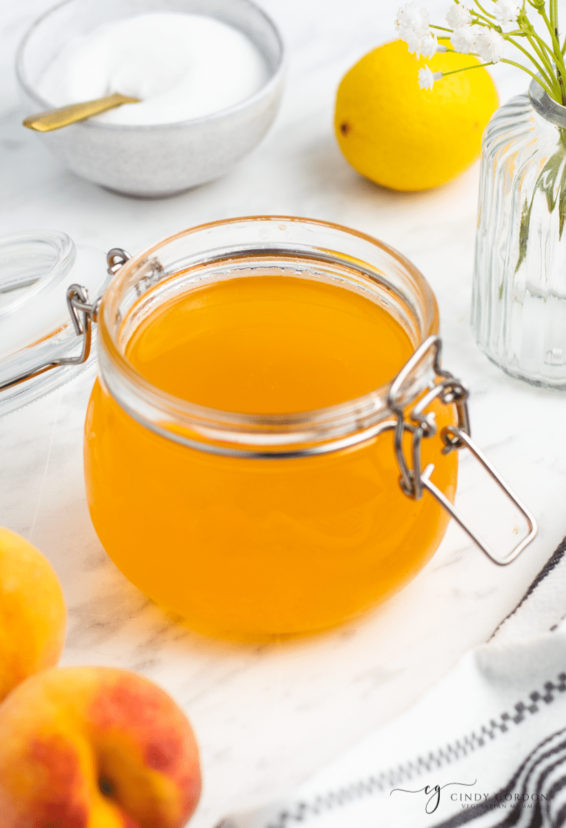 a rounded glass jar with bail top billed with peach simple syrup