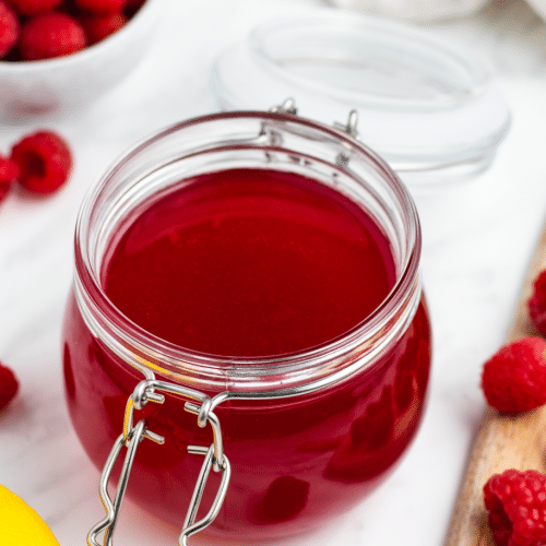 a rounded bail jar full of red raspberry simple syrup