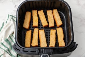 uncooked frozen french toast sticks in air fryer with black basket