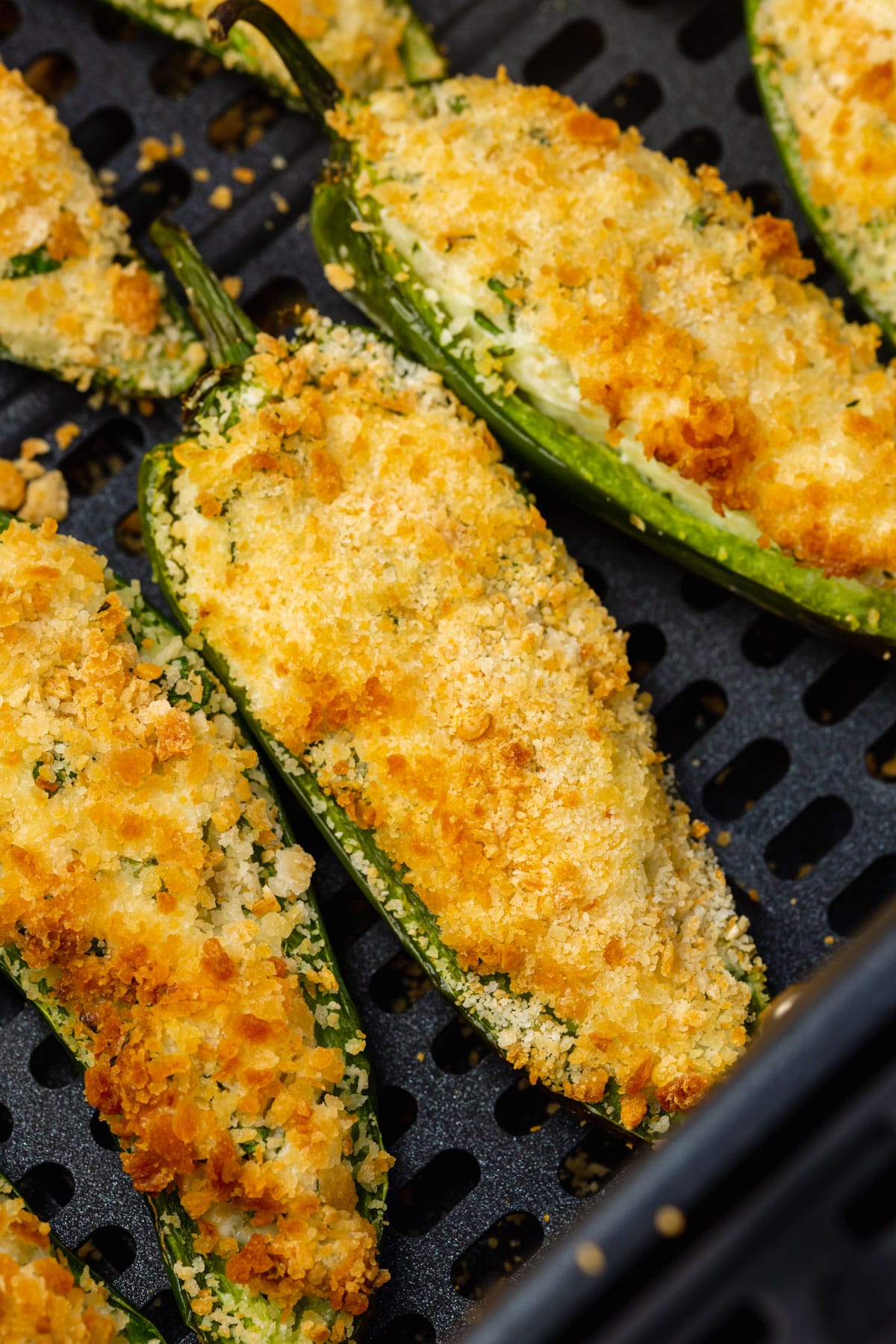 black air fryer basket with golden brown air fried jalapeno poppers