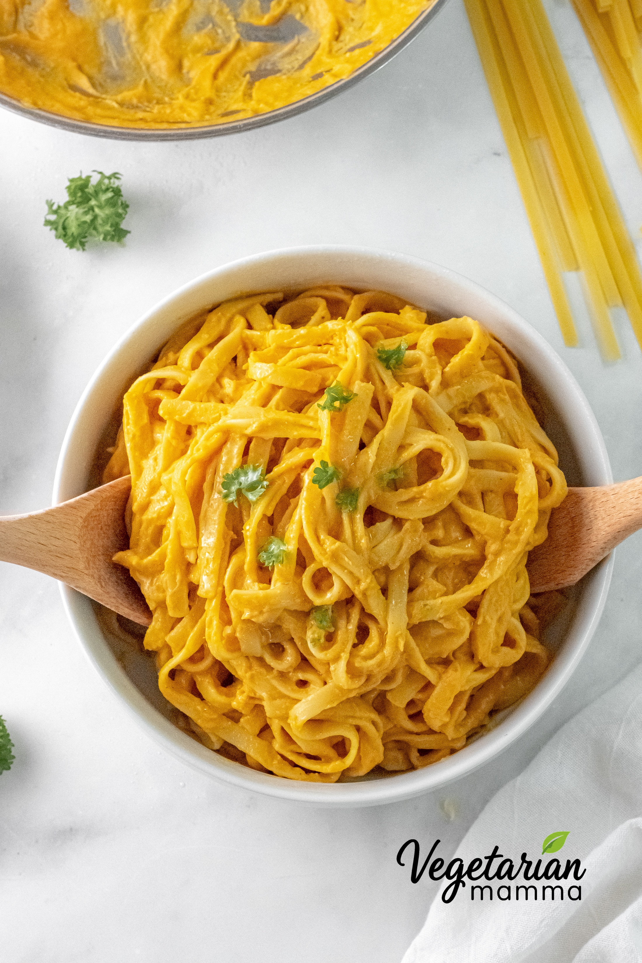 a serving bowl filled with fettuccini with pumpkin alfredo sauce.