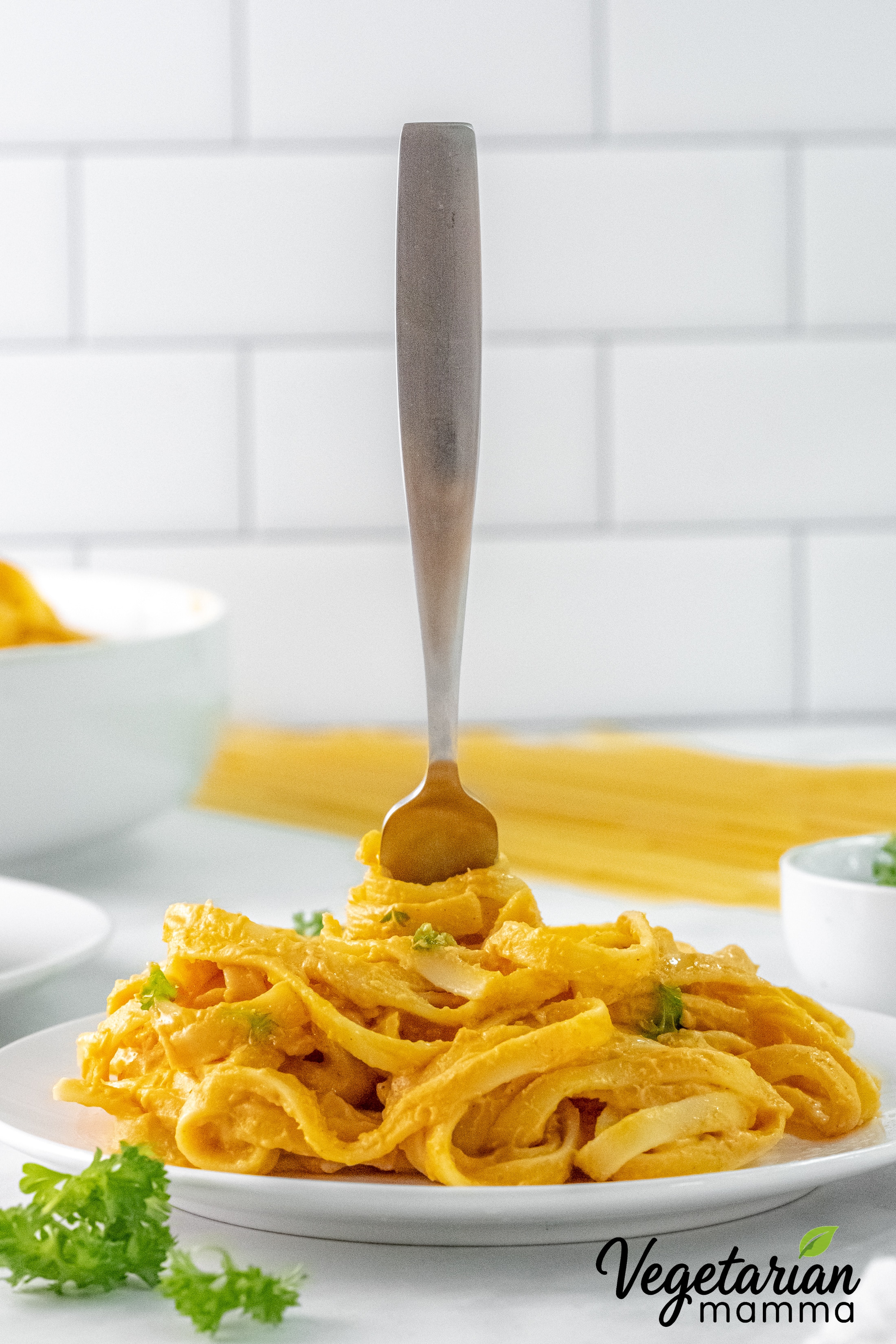 Vegan pumpkin Alfredo served with fettuccine and a fork twirling the pasta.