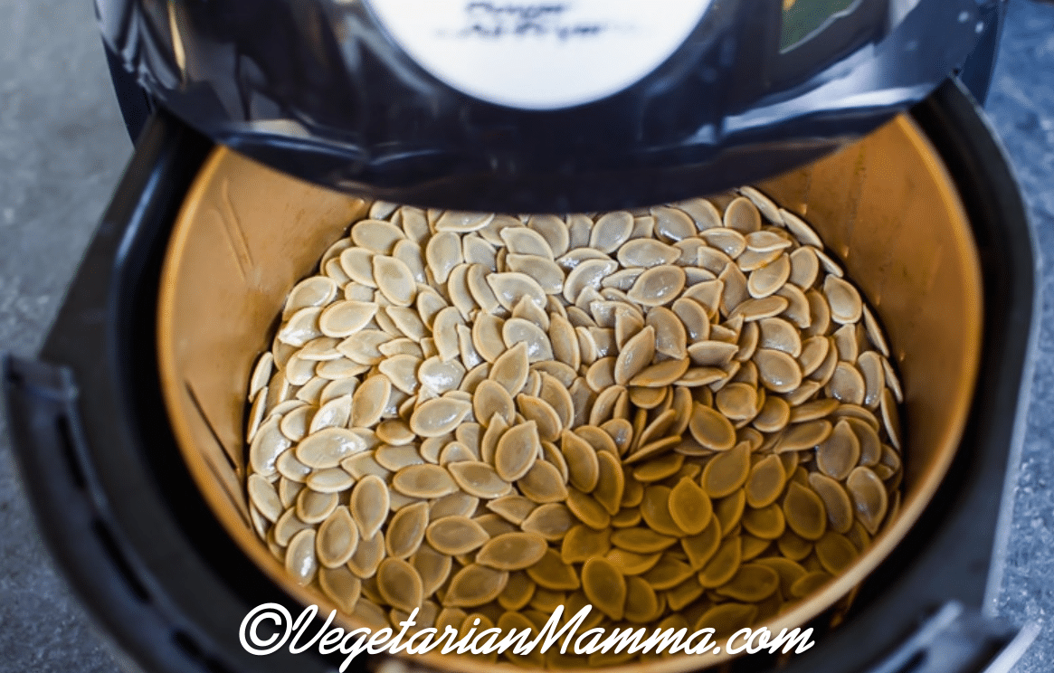 Air Fryer Pumpkin Seeds with seeds in air fryer basket.